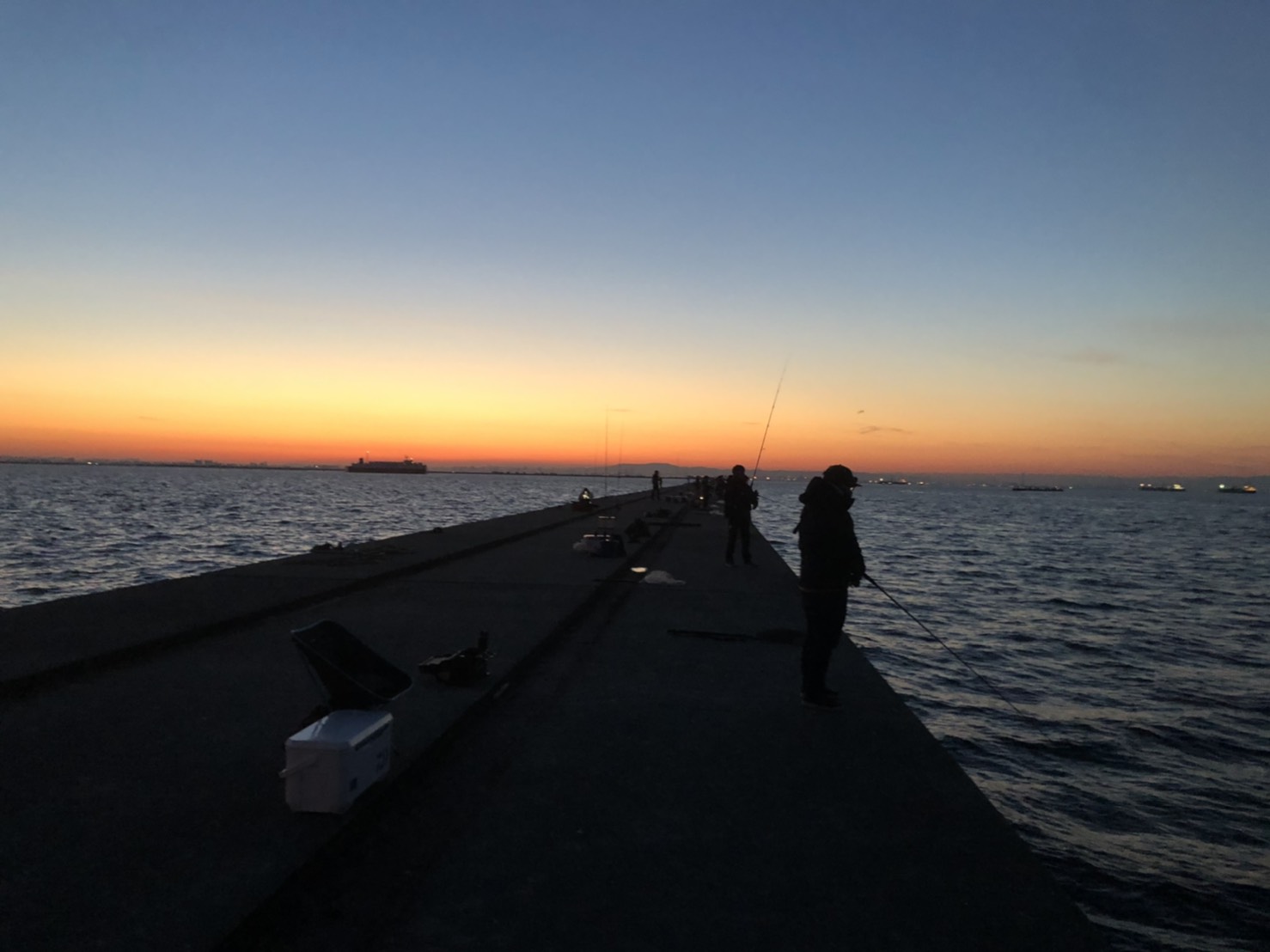 夕暮れの堤防で釣りを楽しむ人々