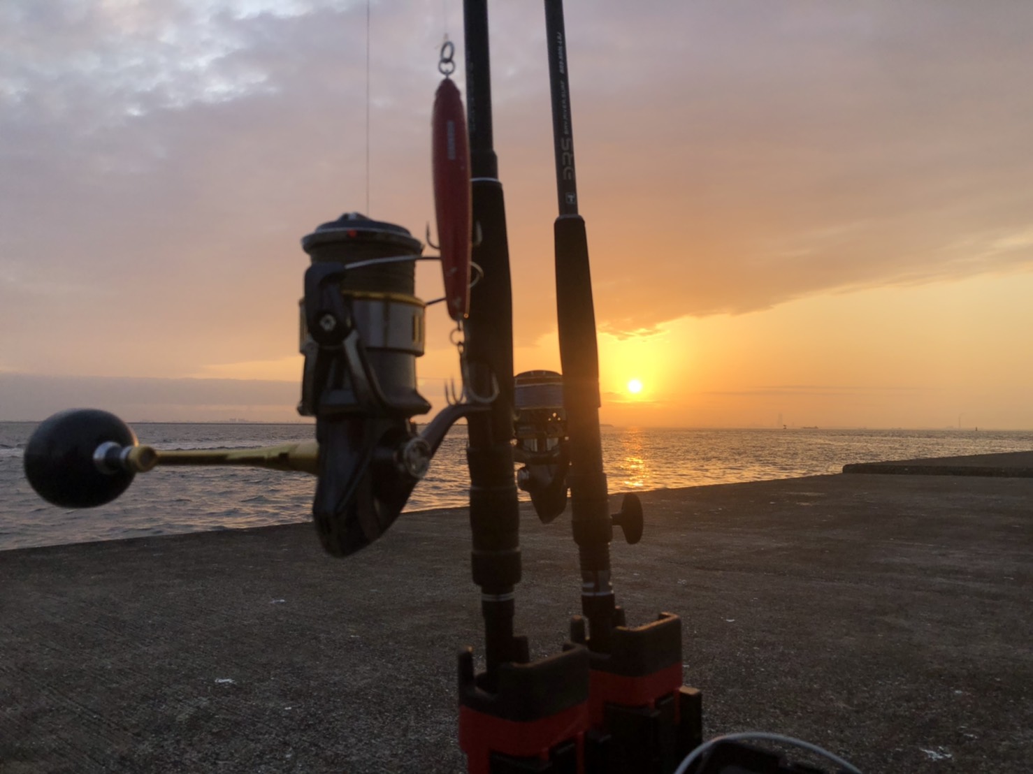 夕日を背景にした釣り竿とリール